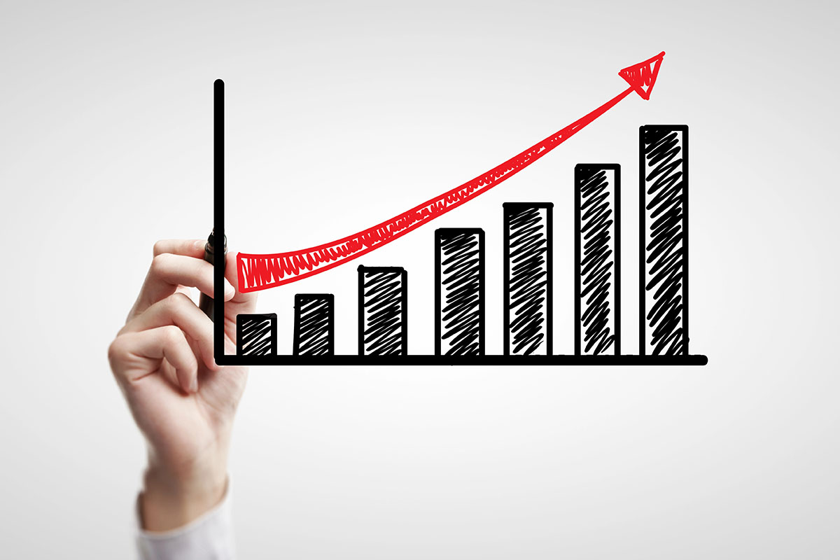 Business Growth Chart A hand is drawing a bar graph showing upwards growth on a dry erase board.