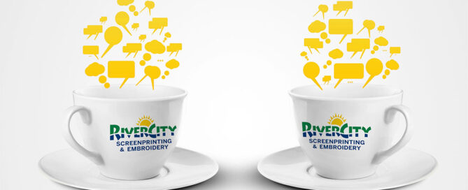 Two coffee mugs showcase RiverCity Screenprinting and Embroidery logos.