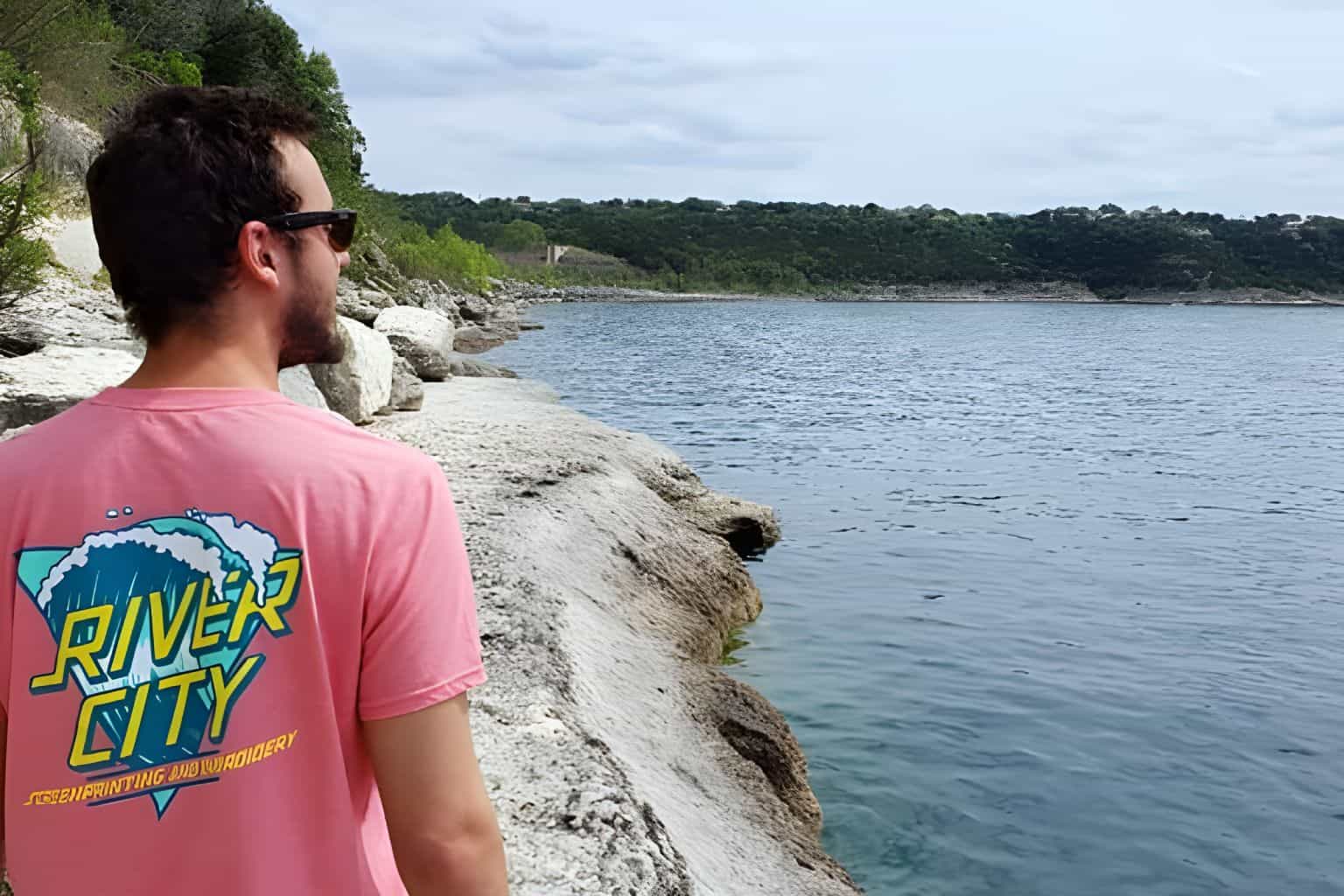 advanced-screen-printing-multi-color A man wearing a t-shirt with a multi-colored screen printed design, looking out over the water.